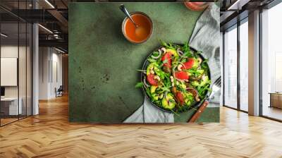 Healthy vegan salad with arugula, avocado, juicy grapefruit, cashews and dressing with olive oil, honey and wine vinegar. Green rustic kitchen table, top view, copy space Wall mural