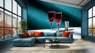 Kir Royale cocktail with black currant liqueur, prosecco wine and red cocktail cherry. Dark green background, hard light and shadow pattern Wall mural