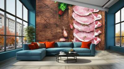 Raw pork chops on rustic wooden cutting board prepared for cooking with garlic, thyme, spices and pepper. Old wood kitchen table,  top view Wall mural