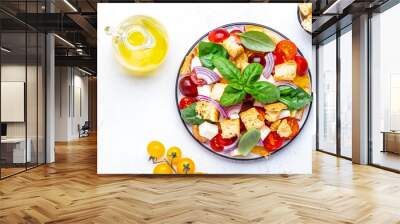 Salad with tomatoes, stale bread, onion, mozzarella cheese, green basil and olive oil, white table background, top view Wall mural