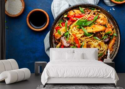 Stir fry egg noodles with chicken, paprika, mushrooms, chives and sesame seeds in ceramic bowl. Asian cuisine dish. Blue stone table background, top view Wall mural