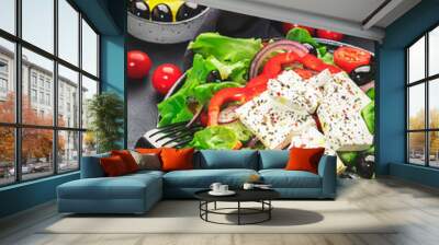 Vegetable greek salad with feta cheese, olives, tomatoes, paprika, cucumber and red onion, healthy mediterranean food, low calories eating. Black table background, top view Wall mural