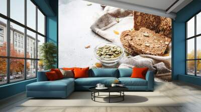 Whole wheat organic rye dark bread with pumpkin seeds, dried fruit, raisins and sesame seeds on gray towel on the kitchen table background, top view. Space for text Wall mural