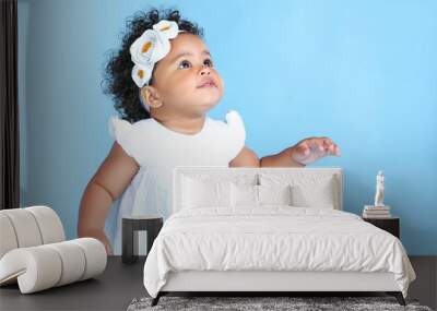 Beautiful baby girl in white dress on blue background Wall mural