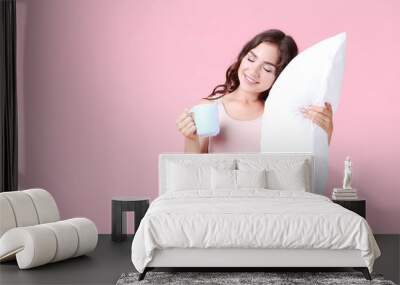 Beautiful girl holding cup of tea and white pillow on pink background Wall mural