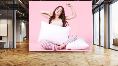 Beautiful girl sitting with white pillows on pink background Wall mural