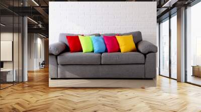 Colorful pillows on grey sofa on a brick wall background Wall mural