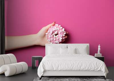 Female hand holding sweet donut on pink background Wall mural