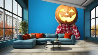 Female hands holding halloween pumpkin on blue background Wall mural