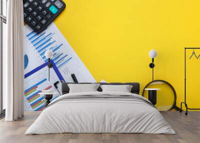 Financial papers with calculator, pen and magnifying glass on yellow background Wall mural