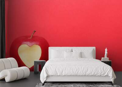 Fresh apple with cutout heart shape on red background Wall mural