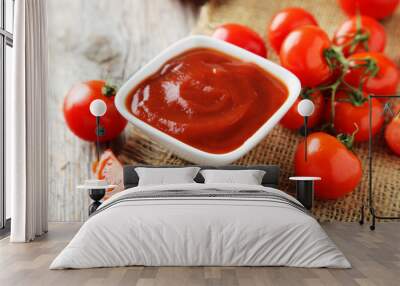 Fresh tomatoes with bowl of ketchup on wooden background Wall mural