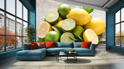 Lemons and limes with green leafs on grey wooden table Wall mural