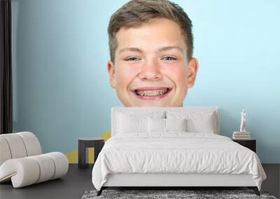 Portrait of young man with dental braces on blue background Wall mural