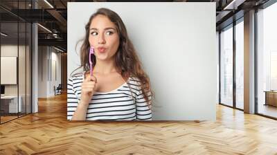 Portrait of young woman with toothbrush on grey background Wall mural