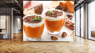 Pumpkin smoothie in glasses with cinnamon and acorns on wooden table Wall mural