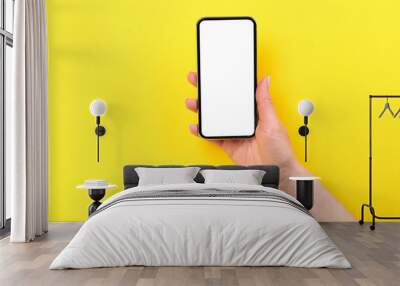 Smartphone in female hand on yellow background Wall mural