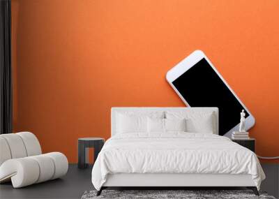 Smartphone with earphones on orange background Wall mural