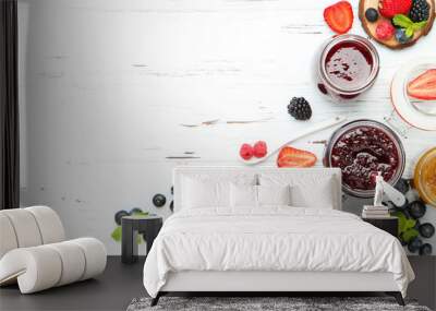 Sweet jam in glass jars with ripe berries on white wooden table Wall mural