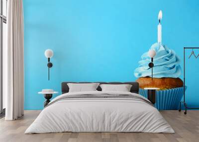 Tasty cupcake with candle on blue background Wall mural