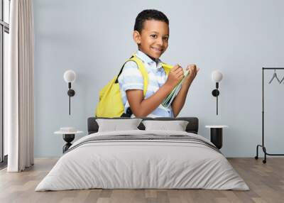 Young African American school boy writing in notepad with backpack on grey background Wall mural