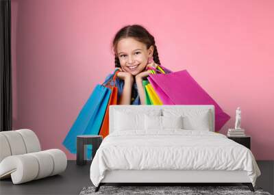 Young girl in denim dress with shopping bags on pink background Wall mural