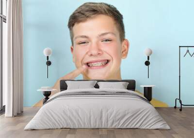 Young man pointing on dental braces on blue background Wall mural