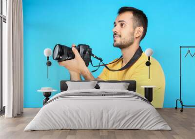 Young photographer with camera on blue background Wall mural