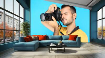 Young photographer with camera on blue background Wall mural