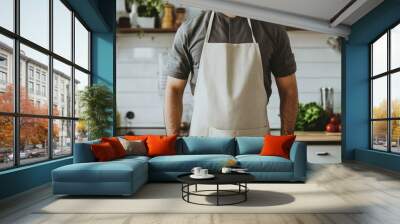 Beige linen apron worn by a man in a modern kitchen setting, ideal for mockups of chef uniforms in a stylish and clean environment Wall mural