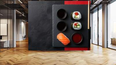 Flat lay of a sushi set with soy sauce and chopsticks on black slate plates, contrasting red and black backgrounds for a modern, Japanese cuisine vibe. Wall mural