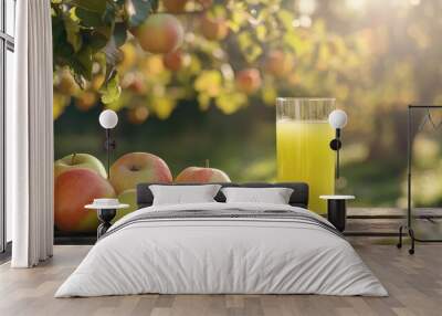 Green apple juice in a clear glass, with crisp apples on a wooden table and a peaceful morning scene with apple trees in the background. Wall mural