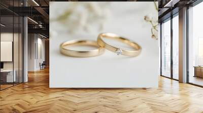 Macro shot of two gold wedding rings on a pristine white background, capturing their elegance and symbolic connection. Wall mural