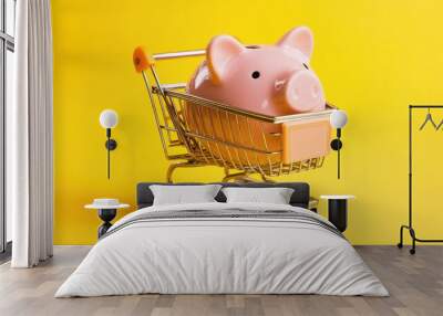 Pink piggy bank in a shopping cart, representing budgeting and smart spending. Isolated on a bright yellow background. Wall mural