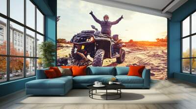 Teen riding ATV in sand dunes making a turn in the sand Wall mural