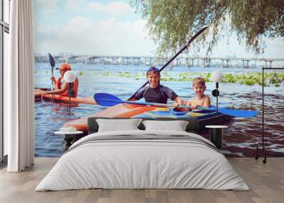 Young people are kayaking on a river in beautiful nature. Wall mural