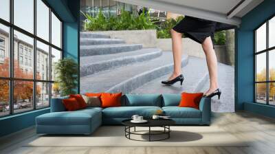 feet and leg of businesswoman wearing black high heel shoes going up the stairs outdoors. woman go to work at office. Wall mural