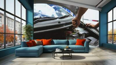 mechanic opening closing checking car battery in automobile repair service Wall mural