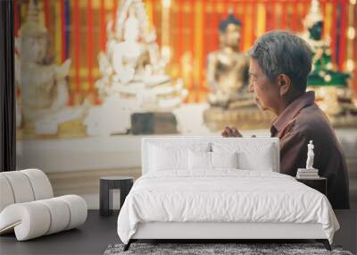 old asian senior woman traveler tourist praying at buddhist temple. Wall mural