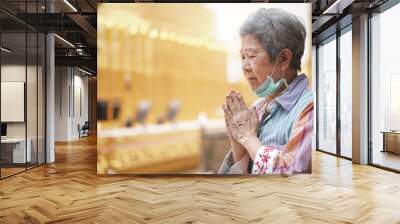 old asian senior woman traveler tourist praying at buddhist temple. Wall mural