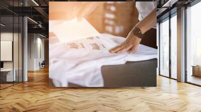 Young woman pull out paper from waterproof film on fabric at shop. worker working on manual screen printing on t-shirt. Wall mural