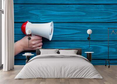 Announcement concept. Megaphone in hand on blue wooden background top view copy space Wall mural