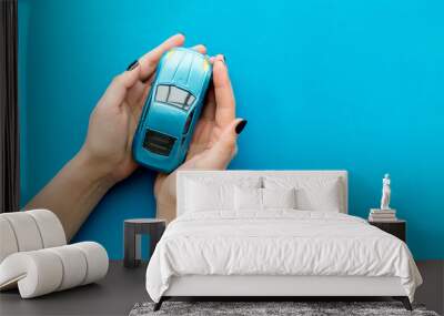 Car insurance concept. Safety of auto. Car toy in female hands on blue background top view copy space Wall mural