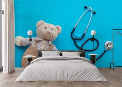 Children's doctor concept. Teddy bear toy and stethoscope on blue background top view space for text Wall mural