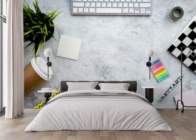 Creative mess on student's desk. Keyboard, notebook, stationery, coffee cup, plant on grey background top view copy space Wall mural