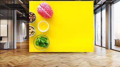 Energy food for brain work with peanut, hazelnut, seed-oil, spinage on yellow background top view space for text Wall mural