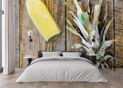 Freshly squeezed pineapple juice near fruit slices on wooden background top view Wall mural