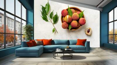 Lychee fruit with green leaf in wooden bowl, top view. Fresh ripe tropical fruit Wall mural