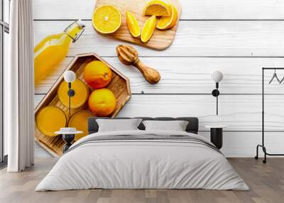 Make orange juice. Juicer, beverage in bottle and glasses near slices of oranges on white wooden background top view copyspace Wall mural