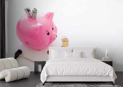 Savings. Moneybox in shape of pig with banknotes falling into it near coins and hammer on white background copy space Wall mural